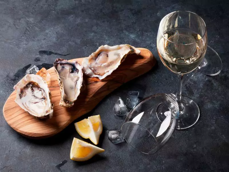 Mesa com ostras frescas e uma taça de vinho Chardonnay