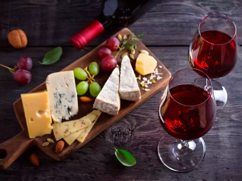 Taças de vinho tinto em mesa com tábua de frios